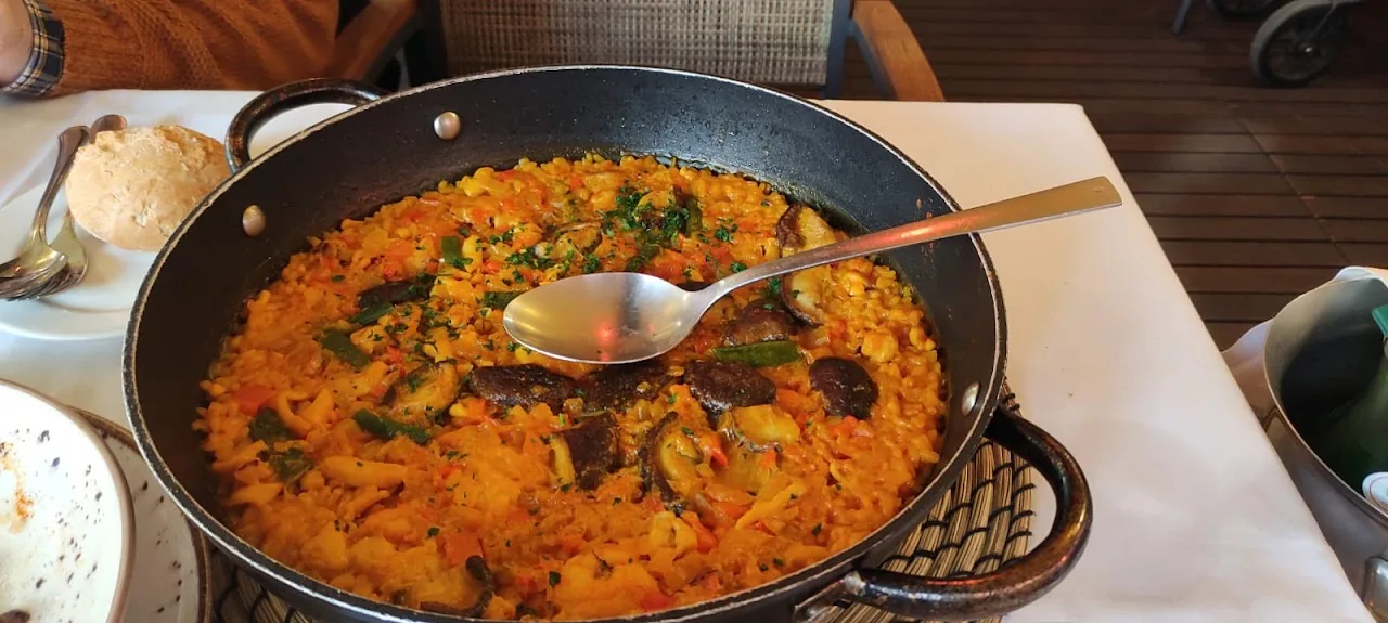 A pan of saffron rice paella with a serving spoon