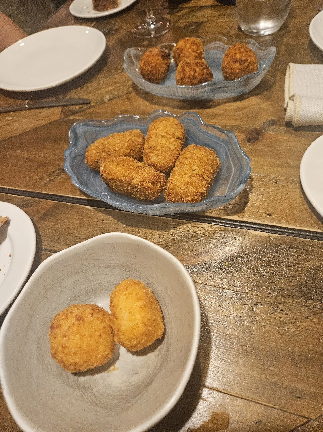 Several golden croquetas on plates on a wooden table