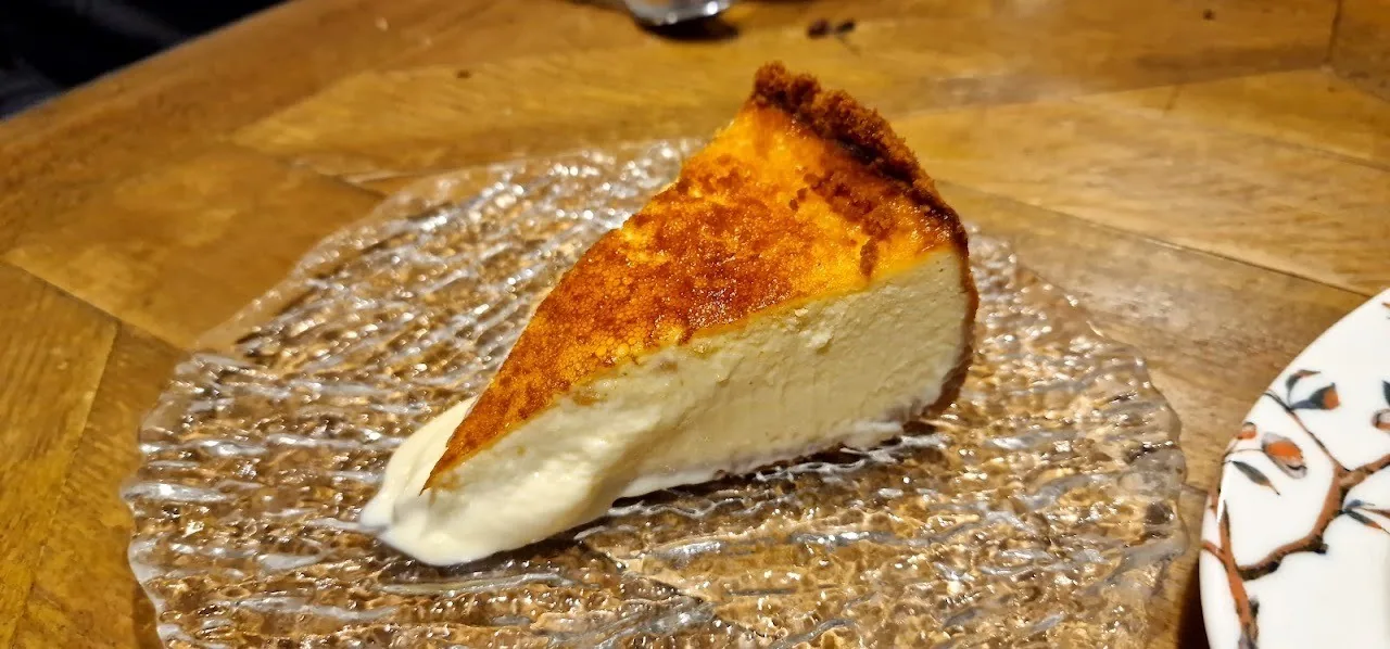 A slice of baked cheesecake with a caramelised top on a glass plate