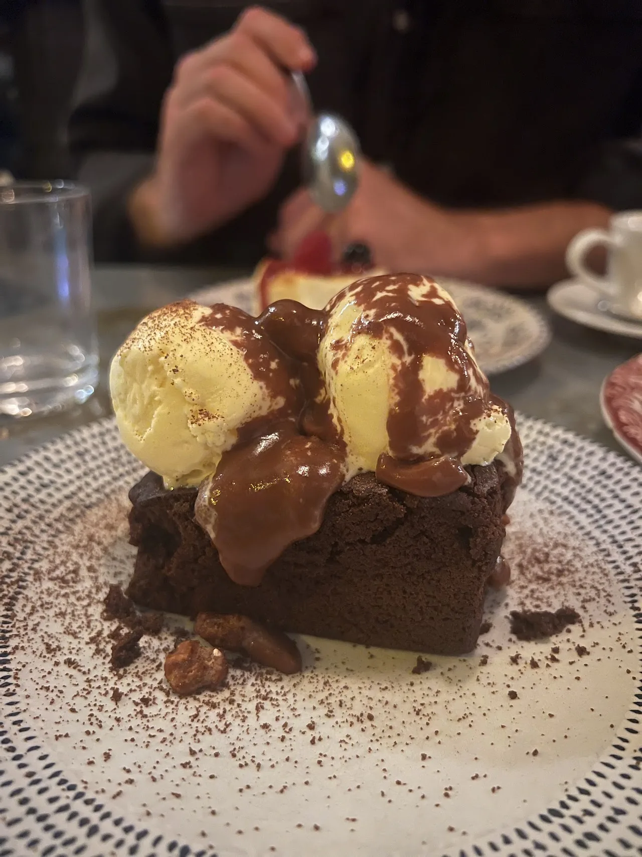 A slice of chocolate cake topped with scoops of vanilla ice cream and chocolate sauce