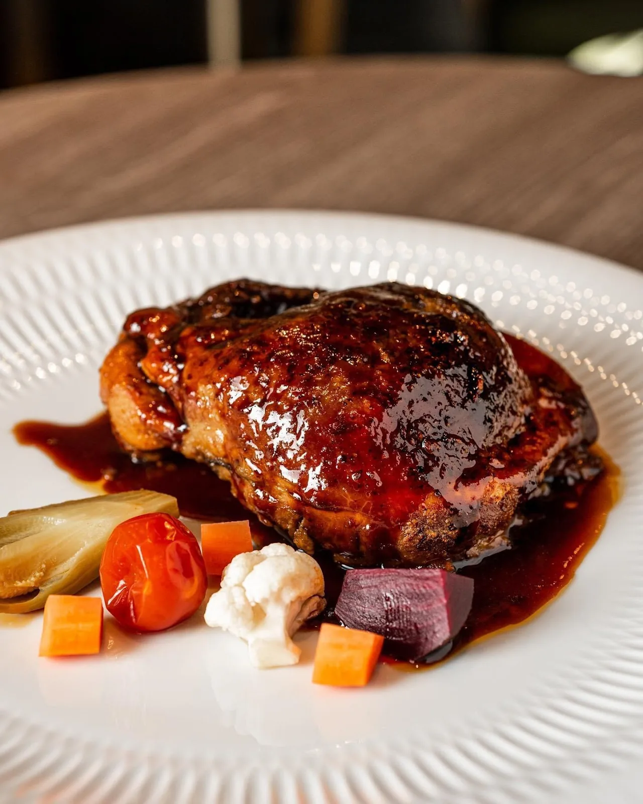 A plated meat dish with roasted vegetables and sauce