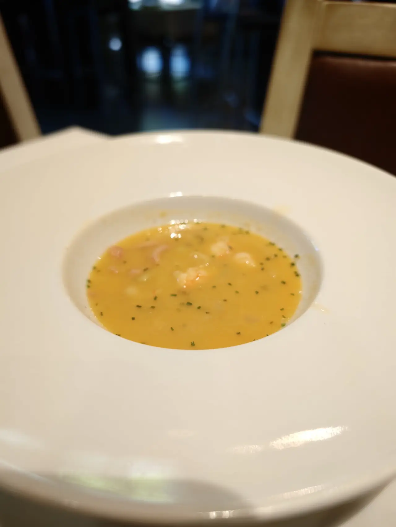 Shrimp bisque with seafood pieces and chives in a wide bowl
