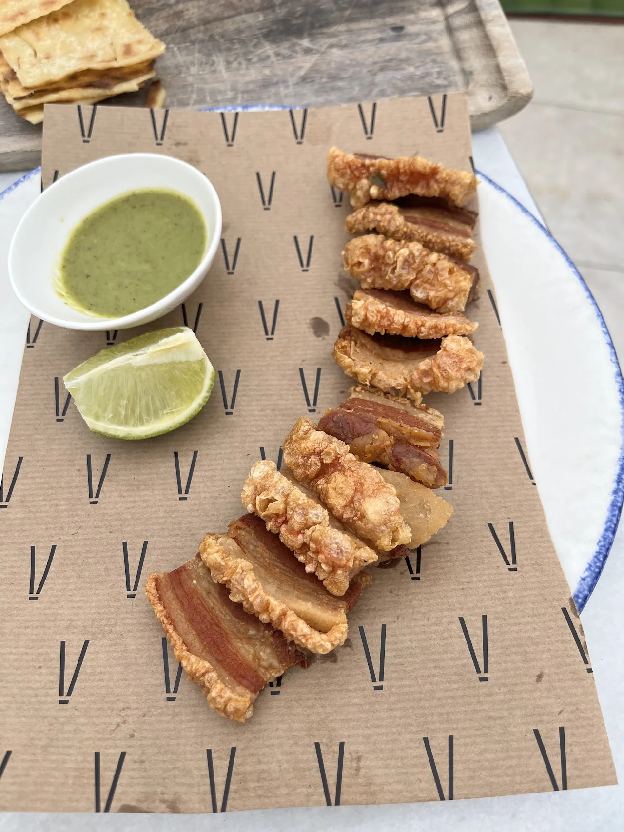 Grilled chicken skewers arranged on a plate with a green dipping sauce and lime wedges