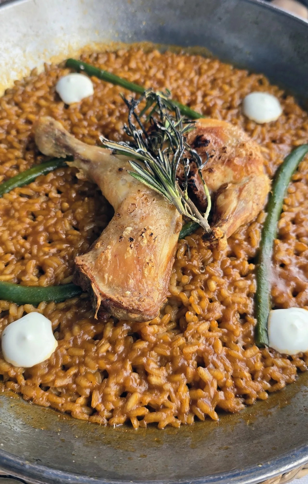 A pan of seafood and chicken paella with a herb garnish