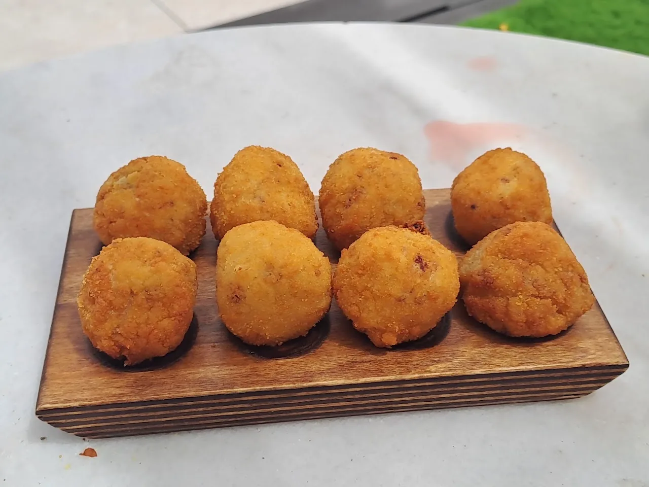 A row of golden fried croquettes on a wooden board