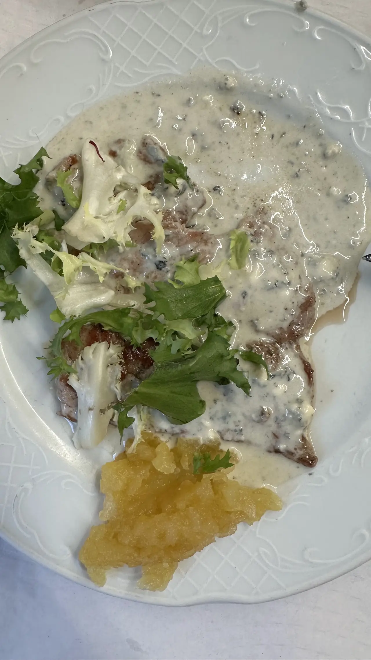Meat in blue cheese sauce with frisee salad and applesauce