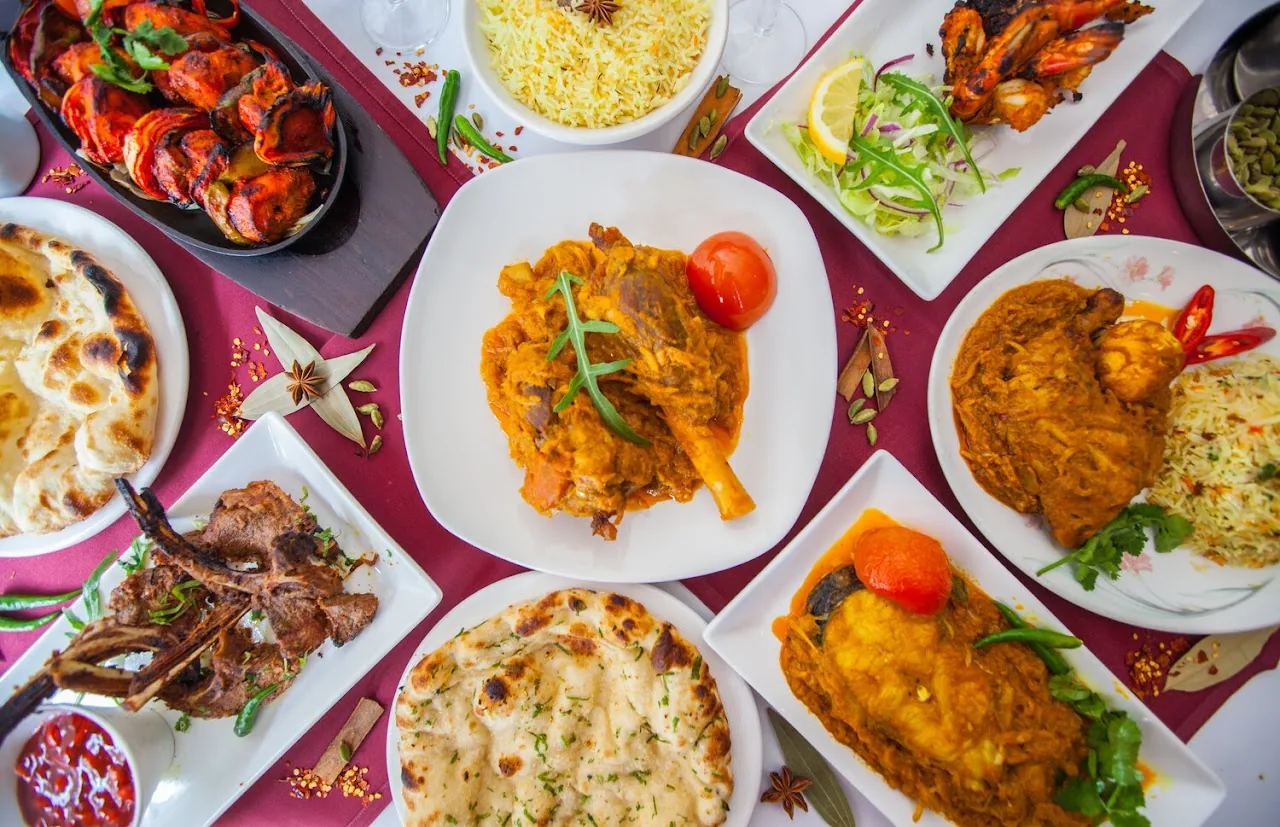 An overhead spread of assorted curry dishes with rice and naan