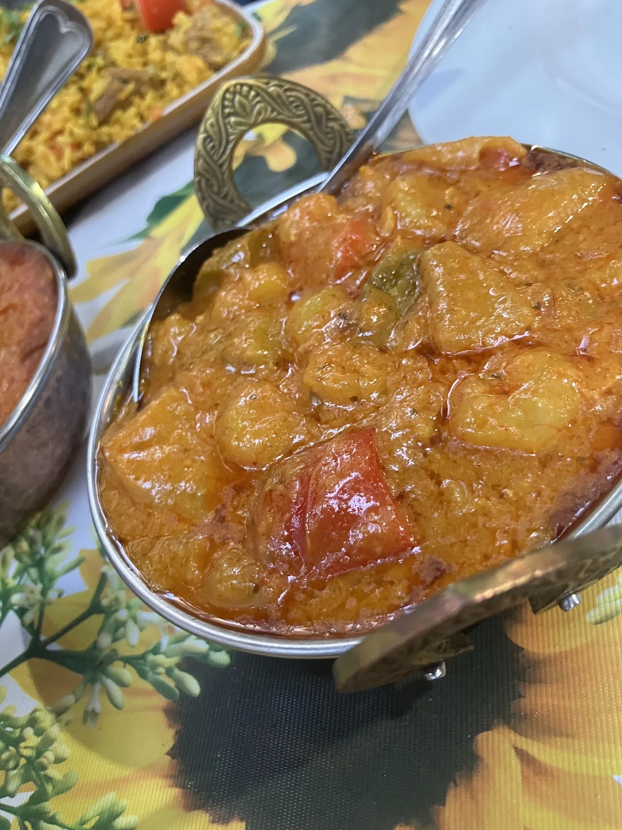 A copper bowl of chicken curry in tomato sauce