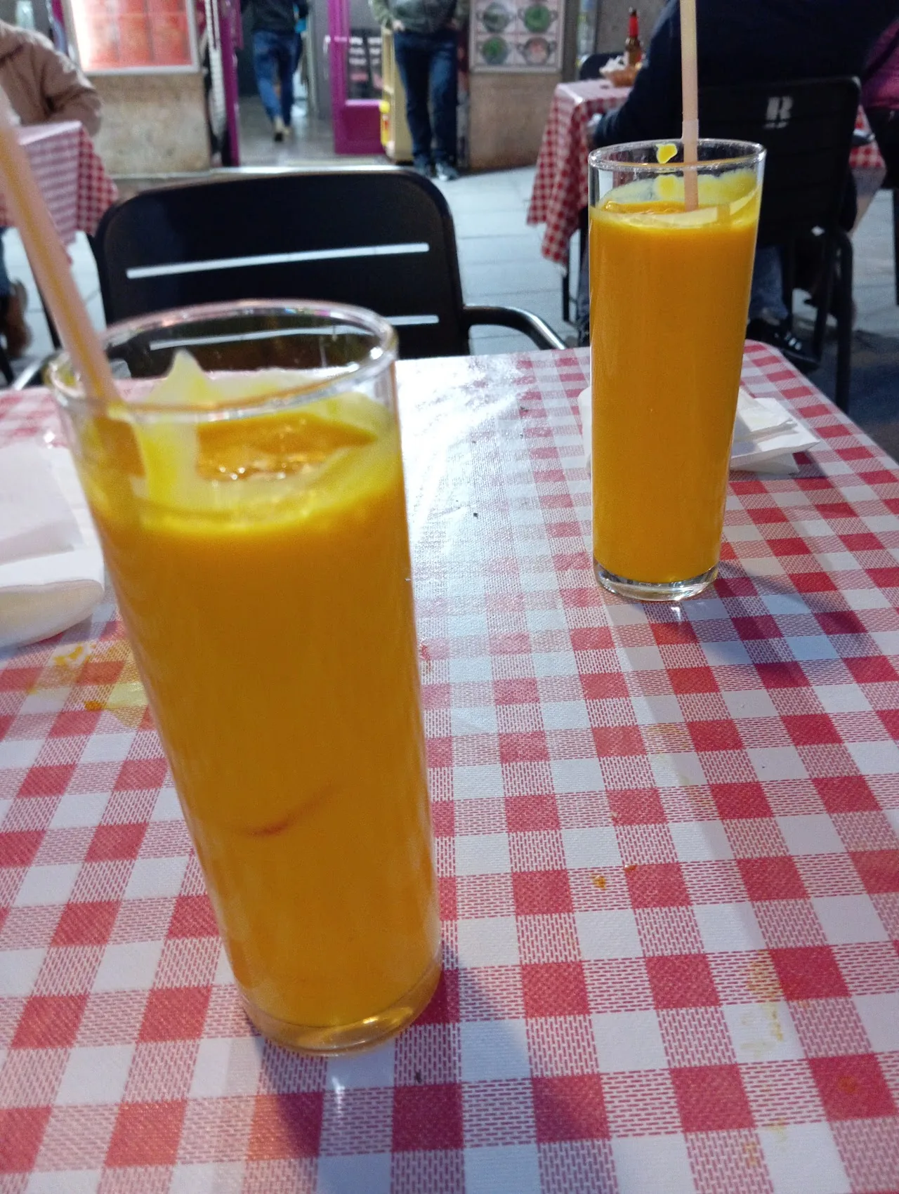 Two glasses of mango lassi on a checkered tablecloth