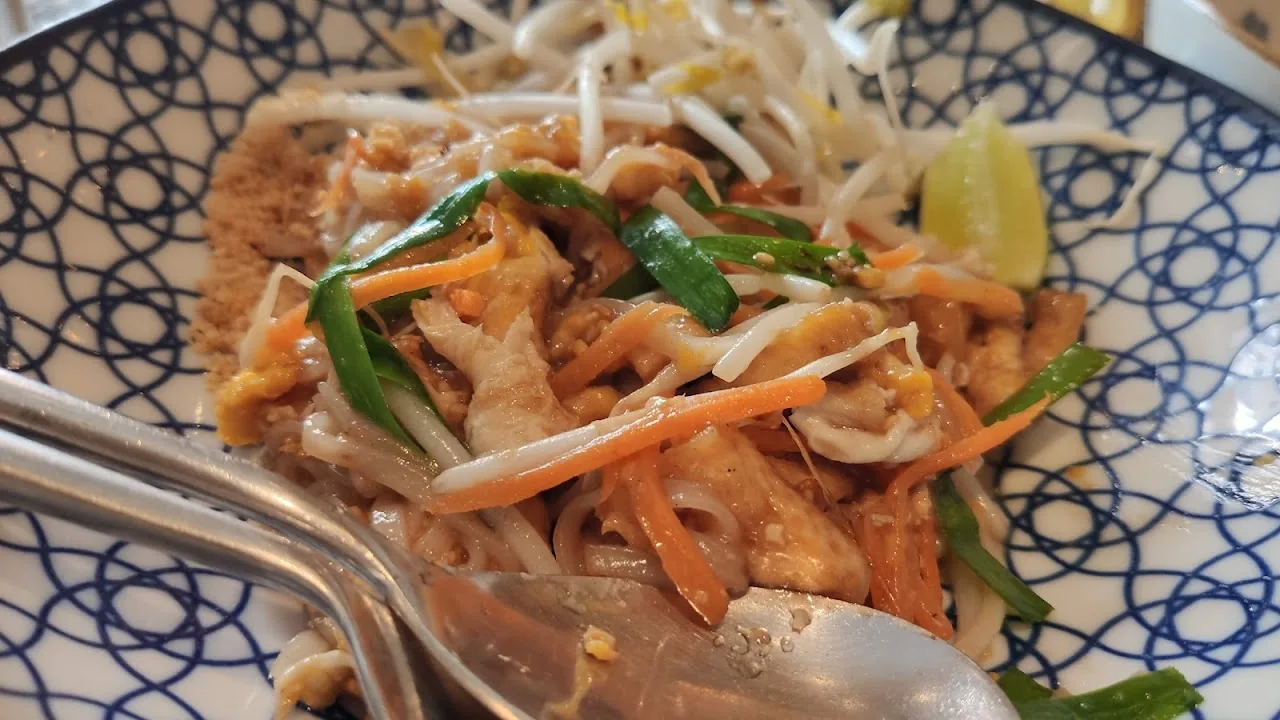 A plate of stir-fried noodles with bean sprouts and herbs