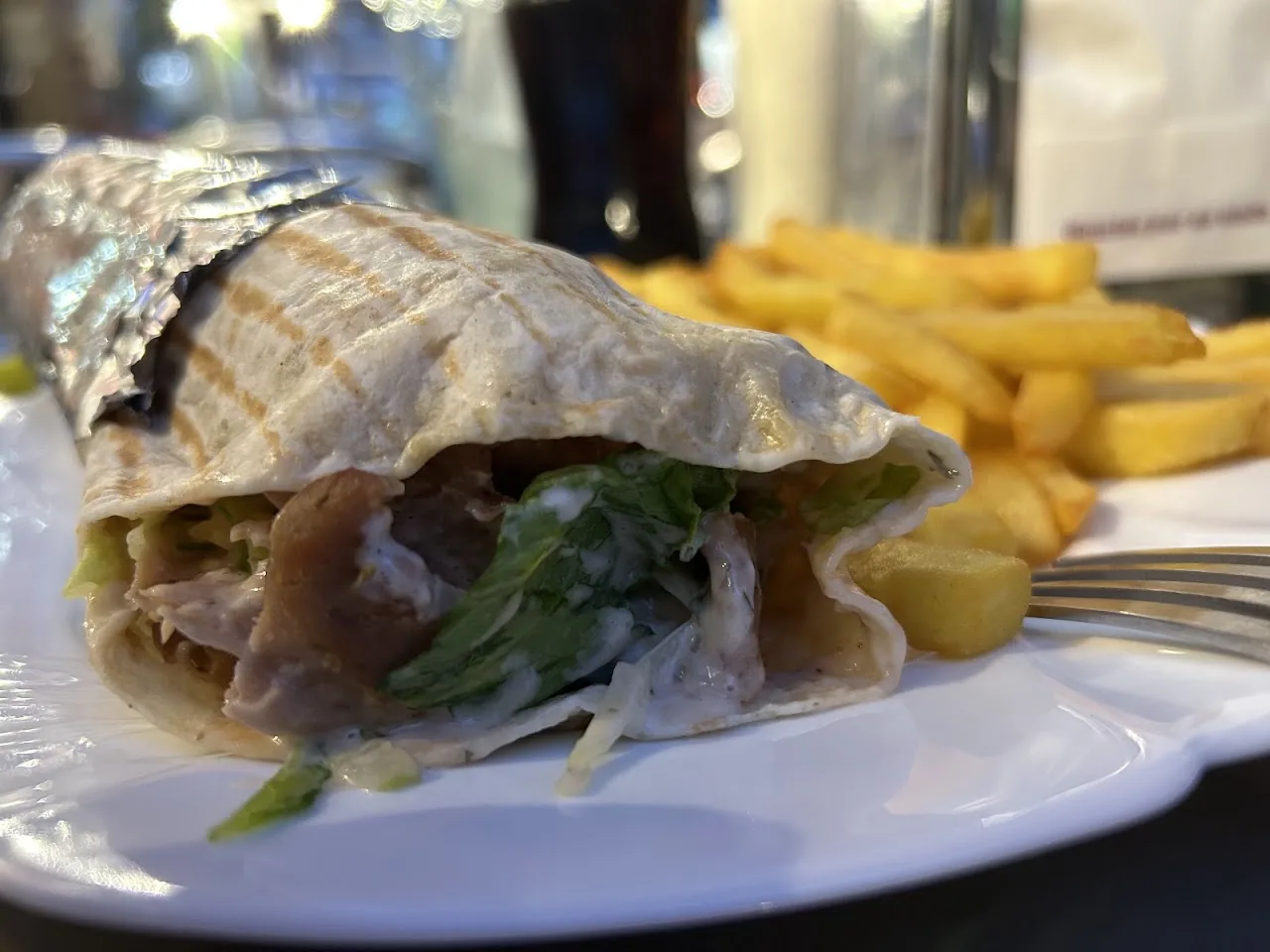 A wrap with greens next to a side of fries