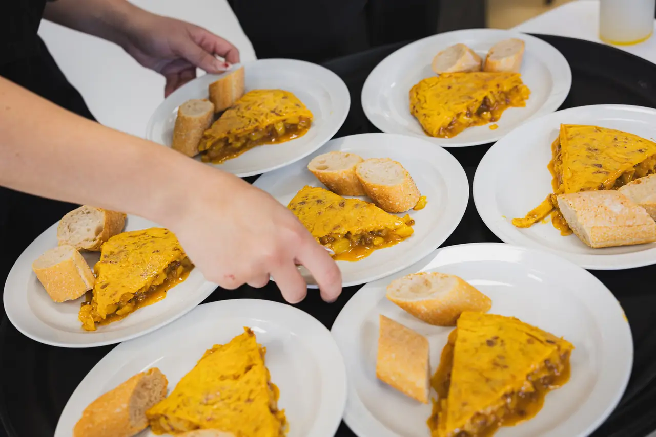Slices of Spanish tortilla with caramelized onion served on white plates alongside pieces of baguette, Bar Bocata