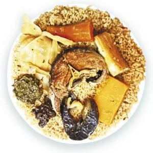 A plate of Senegalese-style rice with a piece of stewed fish, cassava, pumpkin, cabbage, aubergine and a spoonful of green herb paste