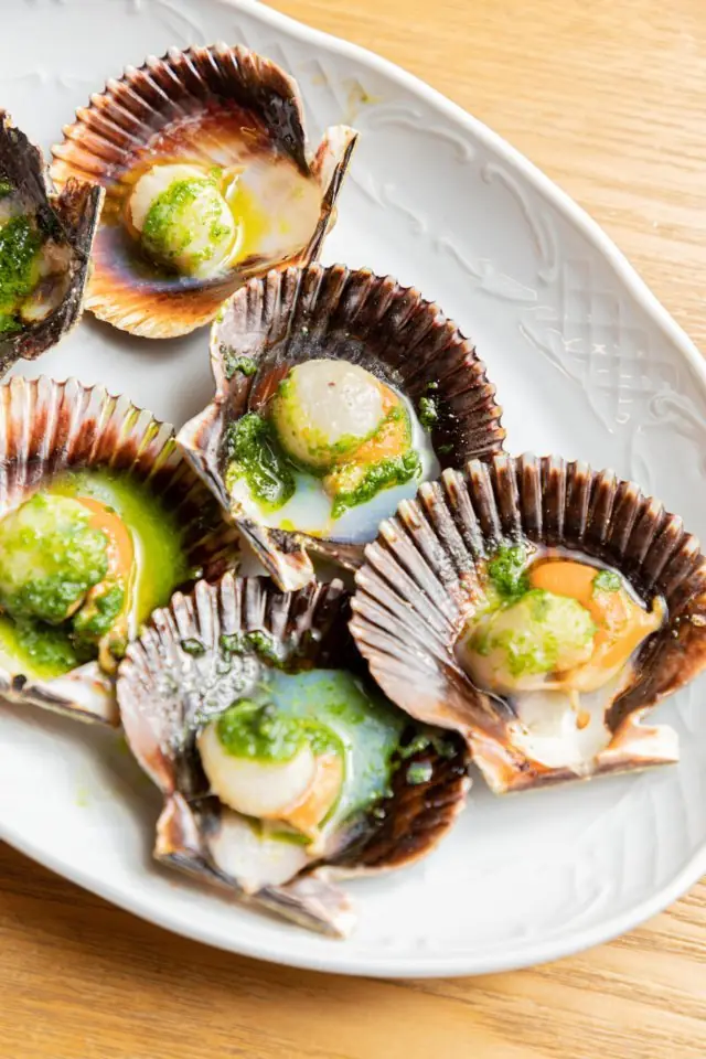 Grilled queen scallops (zamburiñas) in their shells topped with green herb oil at Bar Galán