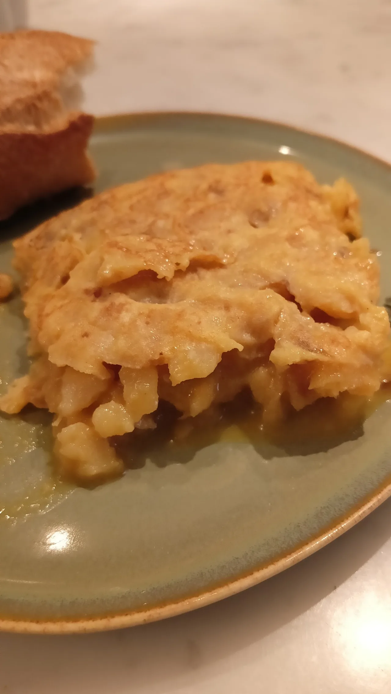 A wedge of potato omelette on a green plate
