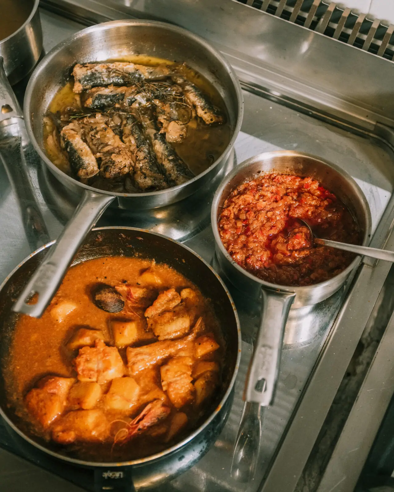 Pans of fried sardines in olive oil and a seafood and potato stew with prawns and clams in a paprika broth, Bar Mundial