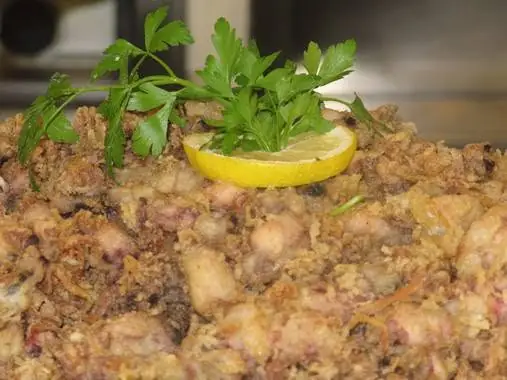 Close-up of fried battered seafood (calamares) topped with a lemon slice and fresh parsley.