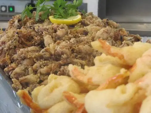 Platter of fried calamares and battered prawns garnished with lemon and parsley, close-up view.