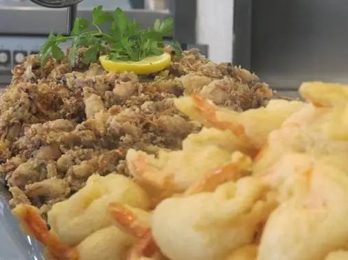 Close-up platter of fried calamares and battered prawns with lemon and parsley garnish.