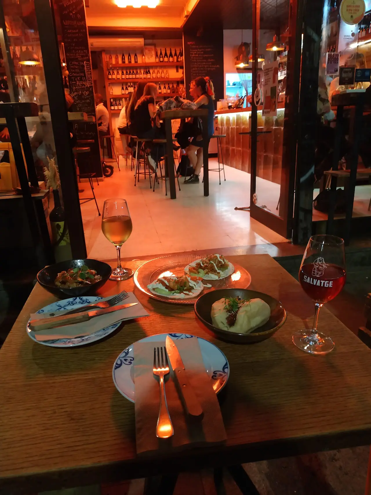 Small tapas plates and a glass of wine on a table at Bar Salvatge.