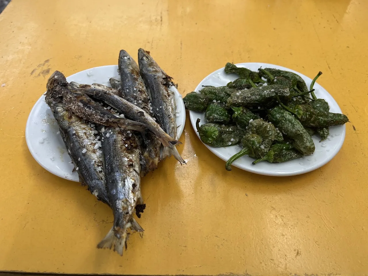 Two plates: grilled sardines and fried green padron peppers