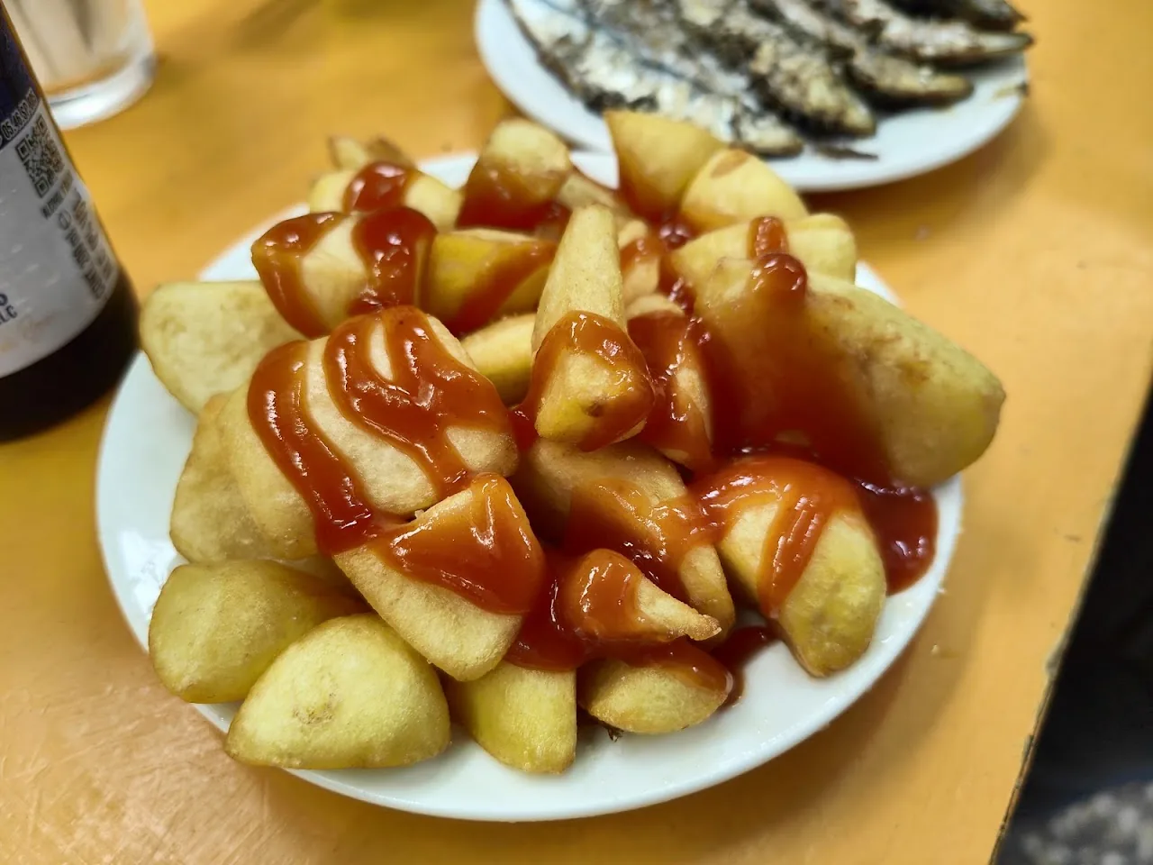A plate of fried potatoes with ketchup drizzled on top