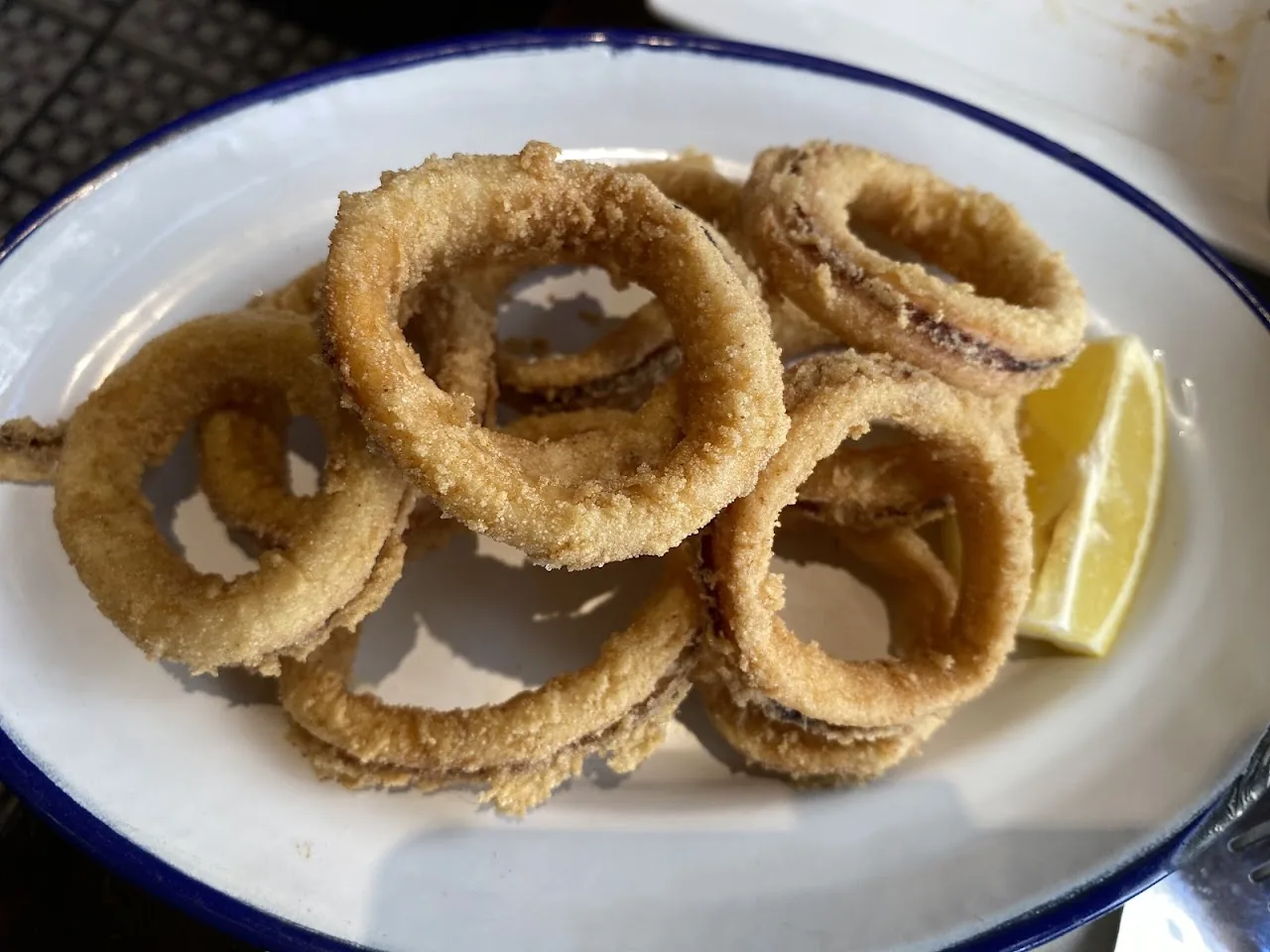 A plate of fried calamari rings with a lemon wedge
