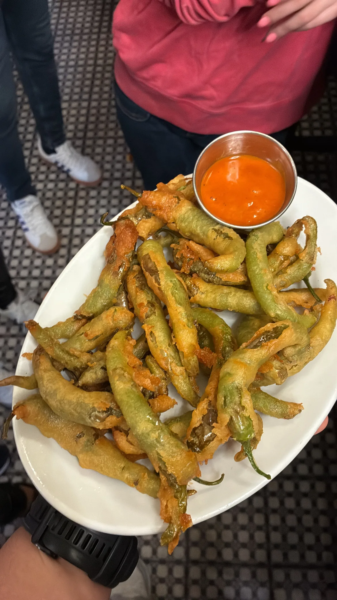 A plate of fried green peppers with a side of red sauce