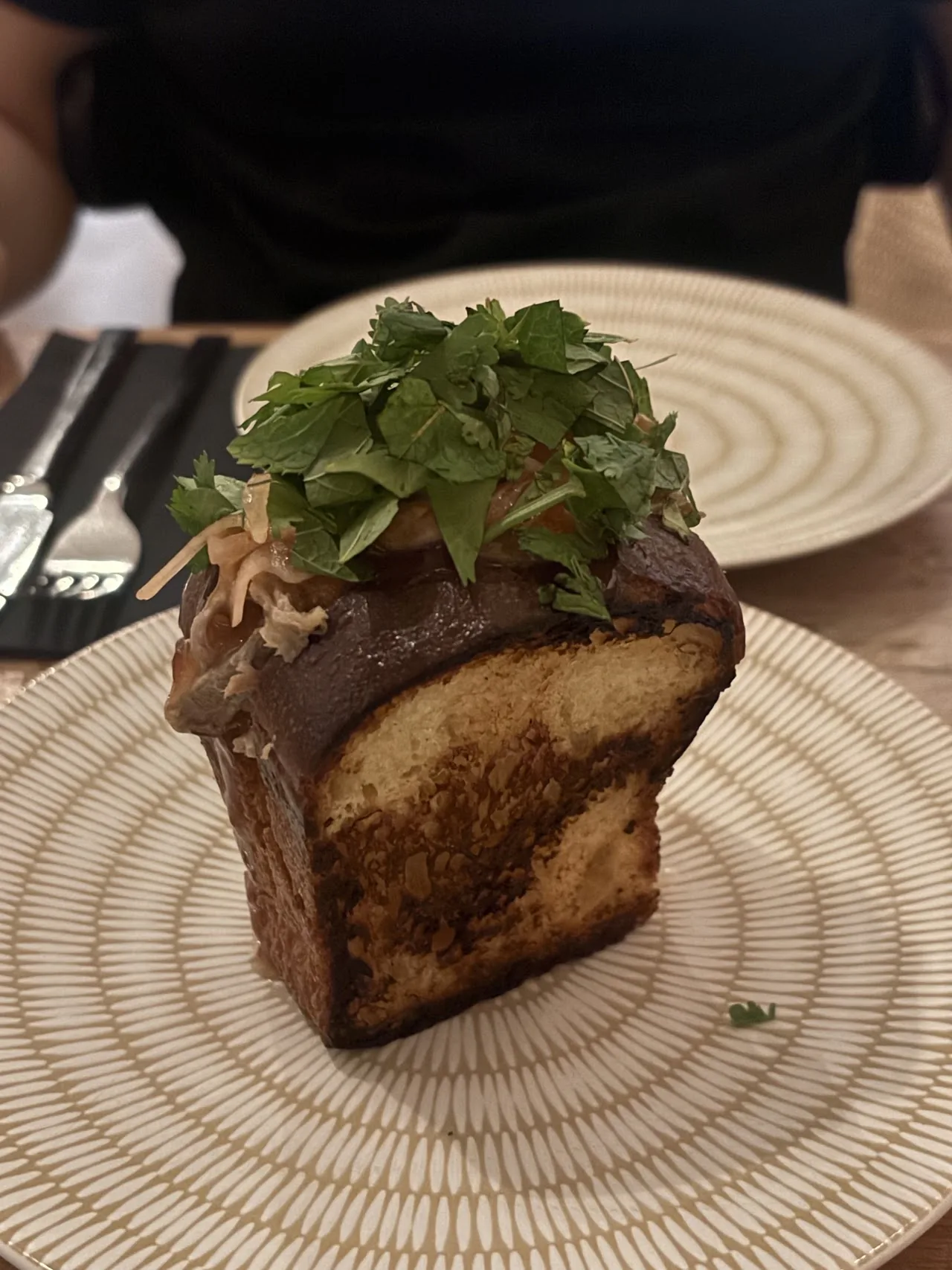 A round sourdough loaf topped with greens and herbs