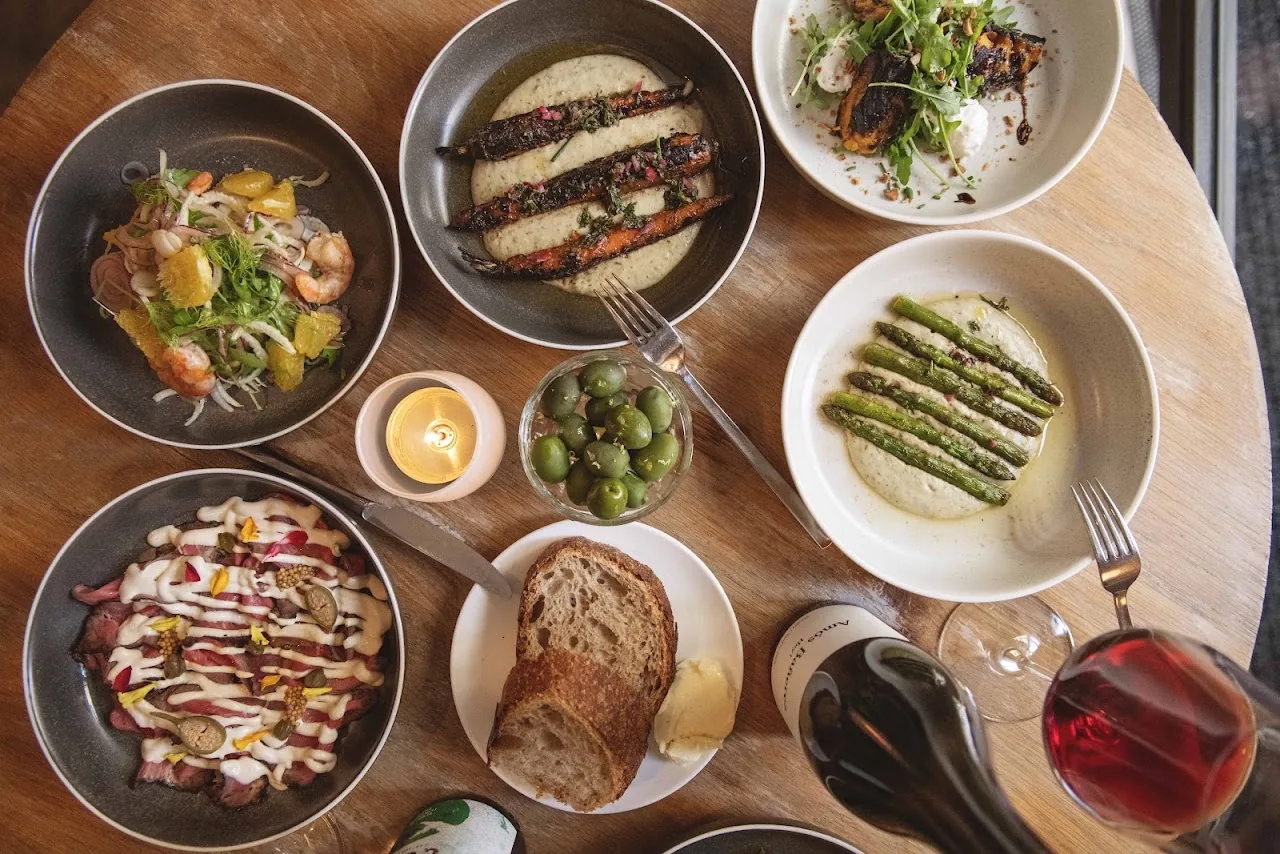 An overhead spread of small plates including salad, toast, olives, and asparagus