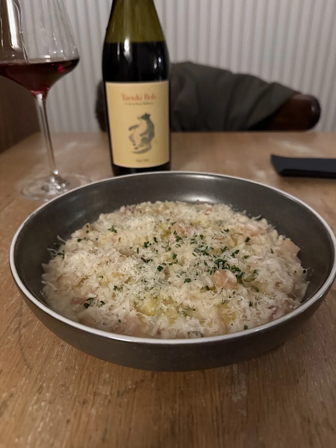 A bowl of creamy risotto next to a glass of red wine