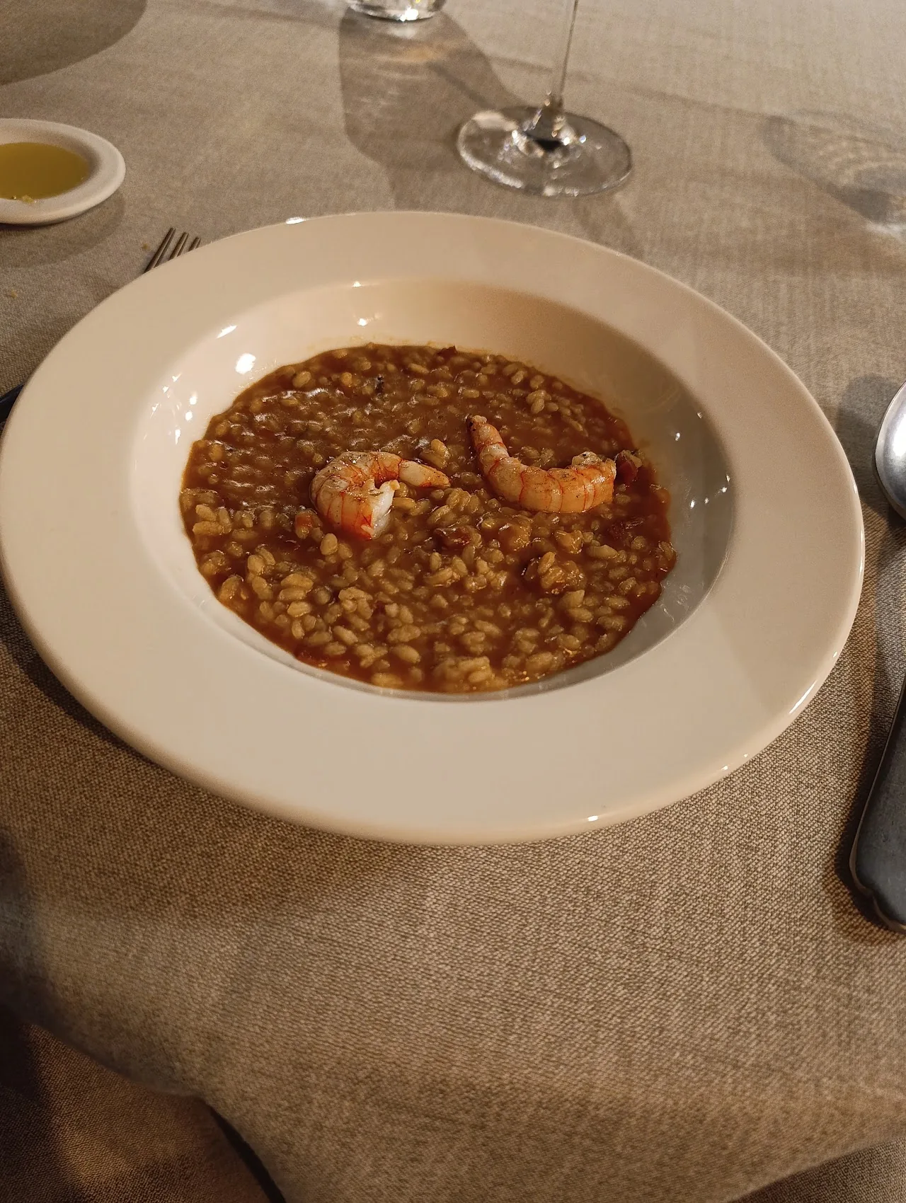 A creamy rice dish topped with whole prawns in a white bowl