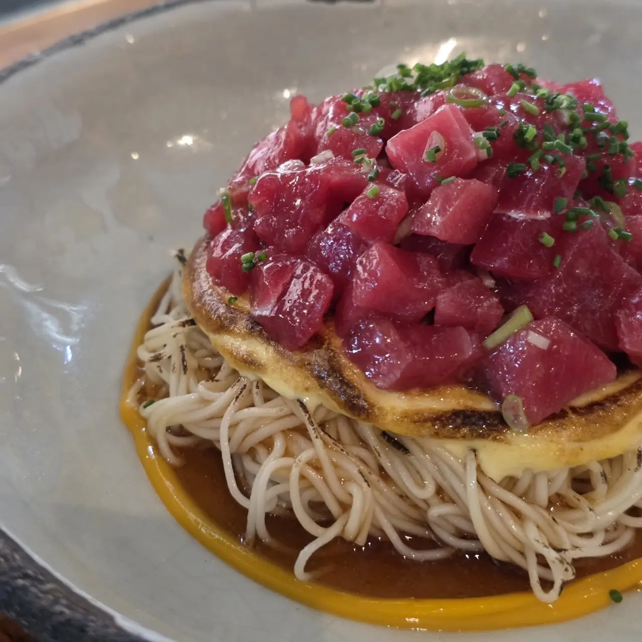 Diced raw tuna over crispy noodles with a golden sauce
