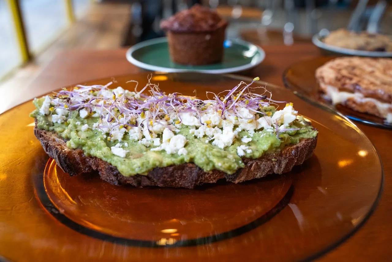 Avocado toast topped with edible flowers and microgreens on a wooden board