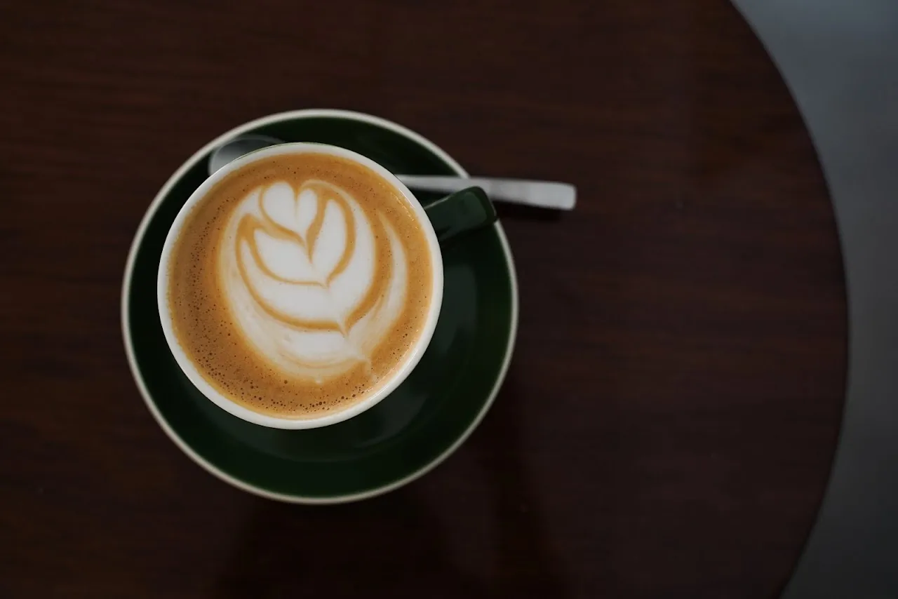A cappuccino with latte art in a green cup, seen from above