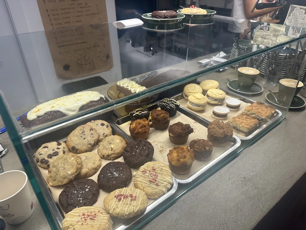 A bakery display case with assorted cookies and muffins