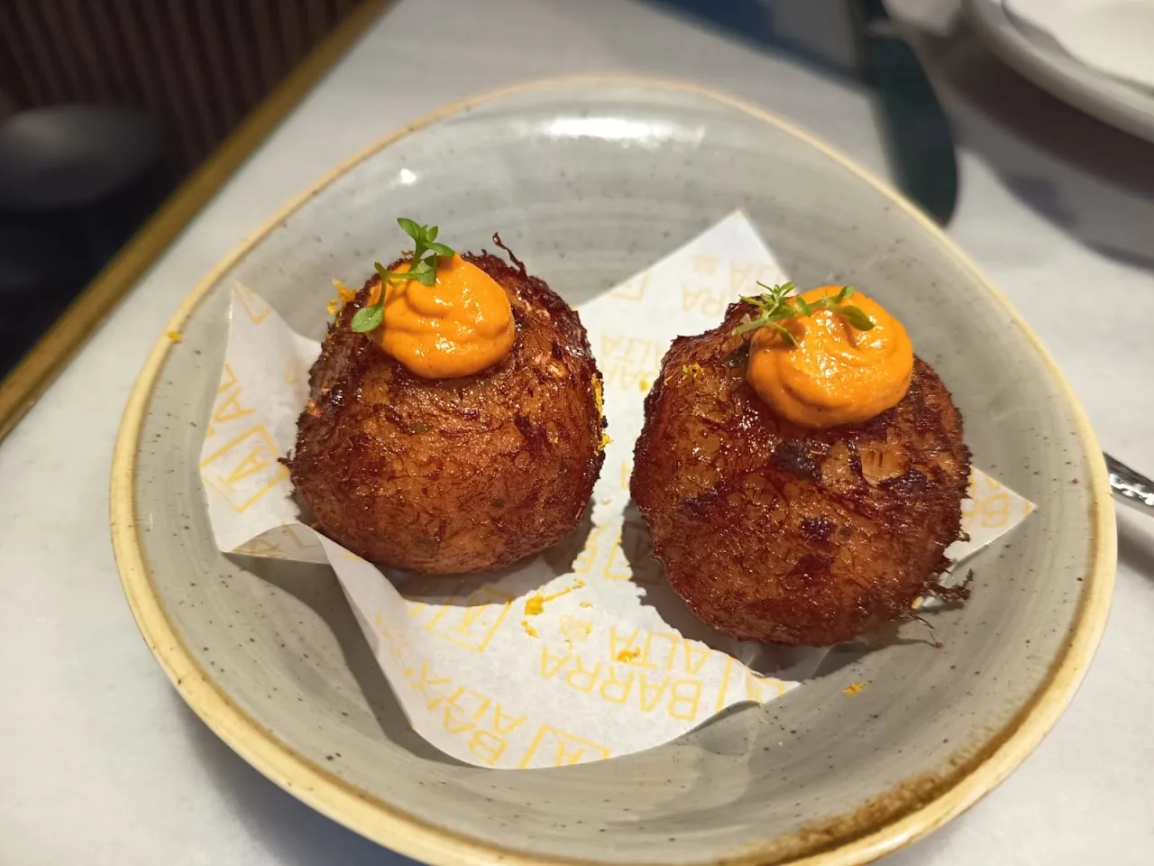 Two crispy croquettes topped with orange sauce