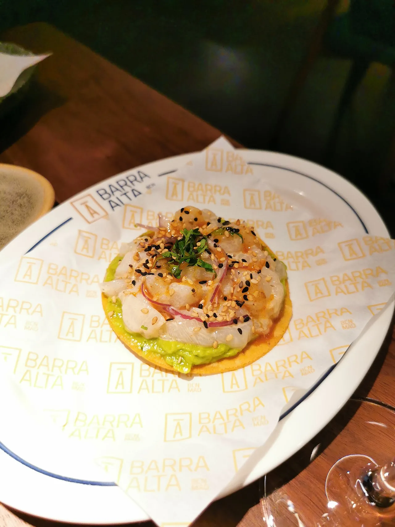 A tostada topped with shredded fish, sesame seeds, and herbs