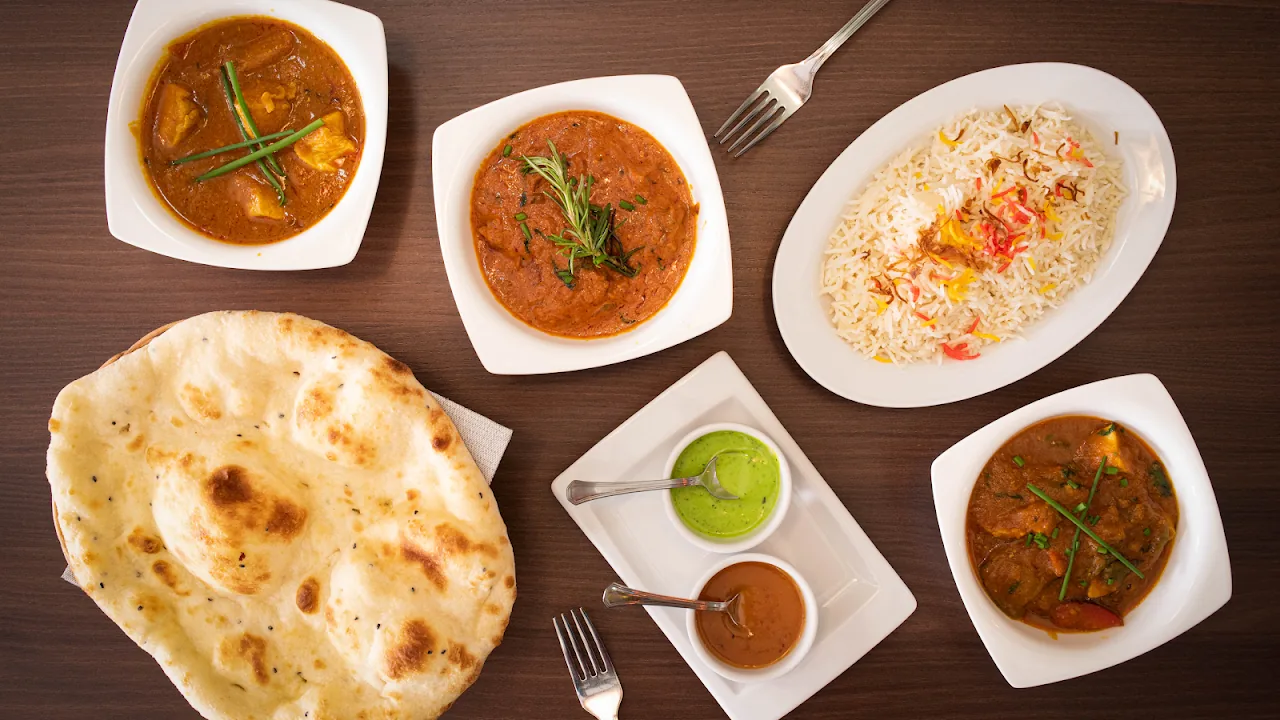 An overhead spread of curries, rice, and naan bread