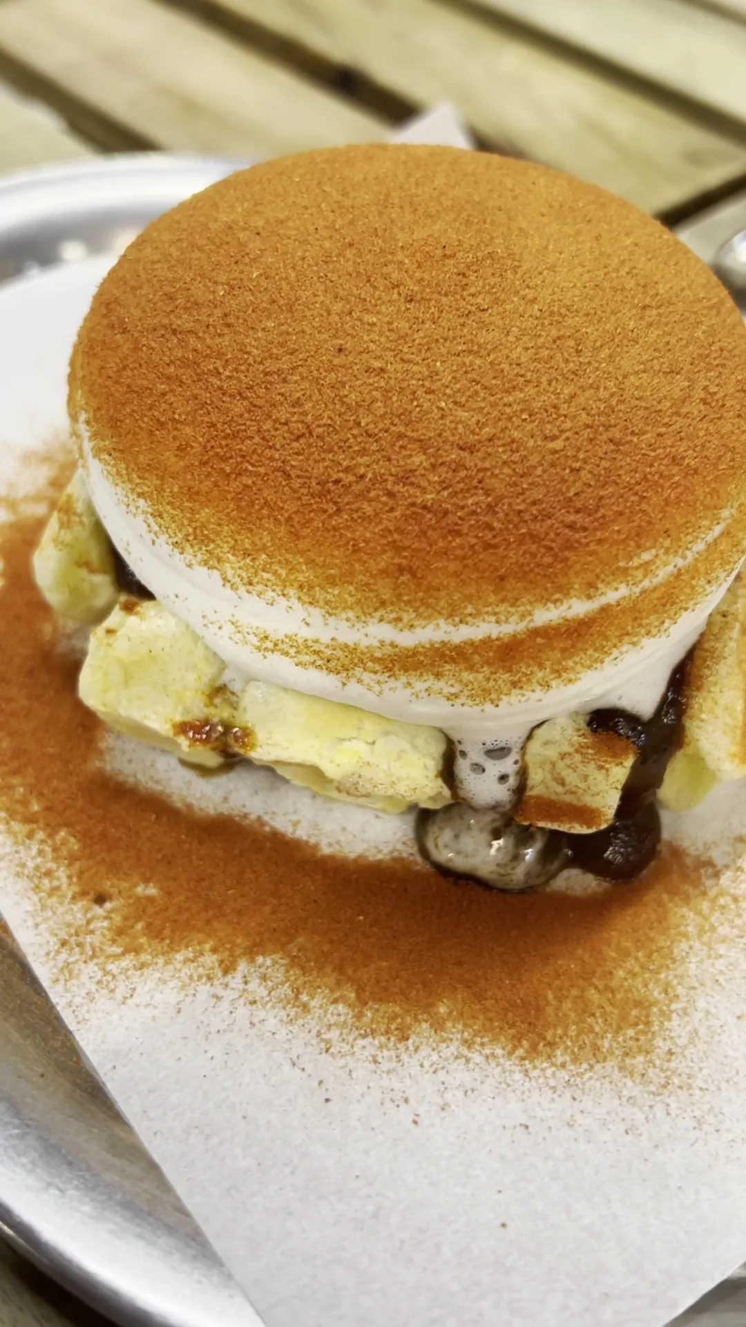 A stacked pancake dessert dusted with cocoa and topped with banana slices