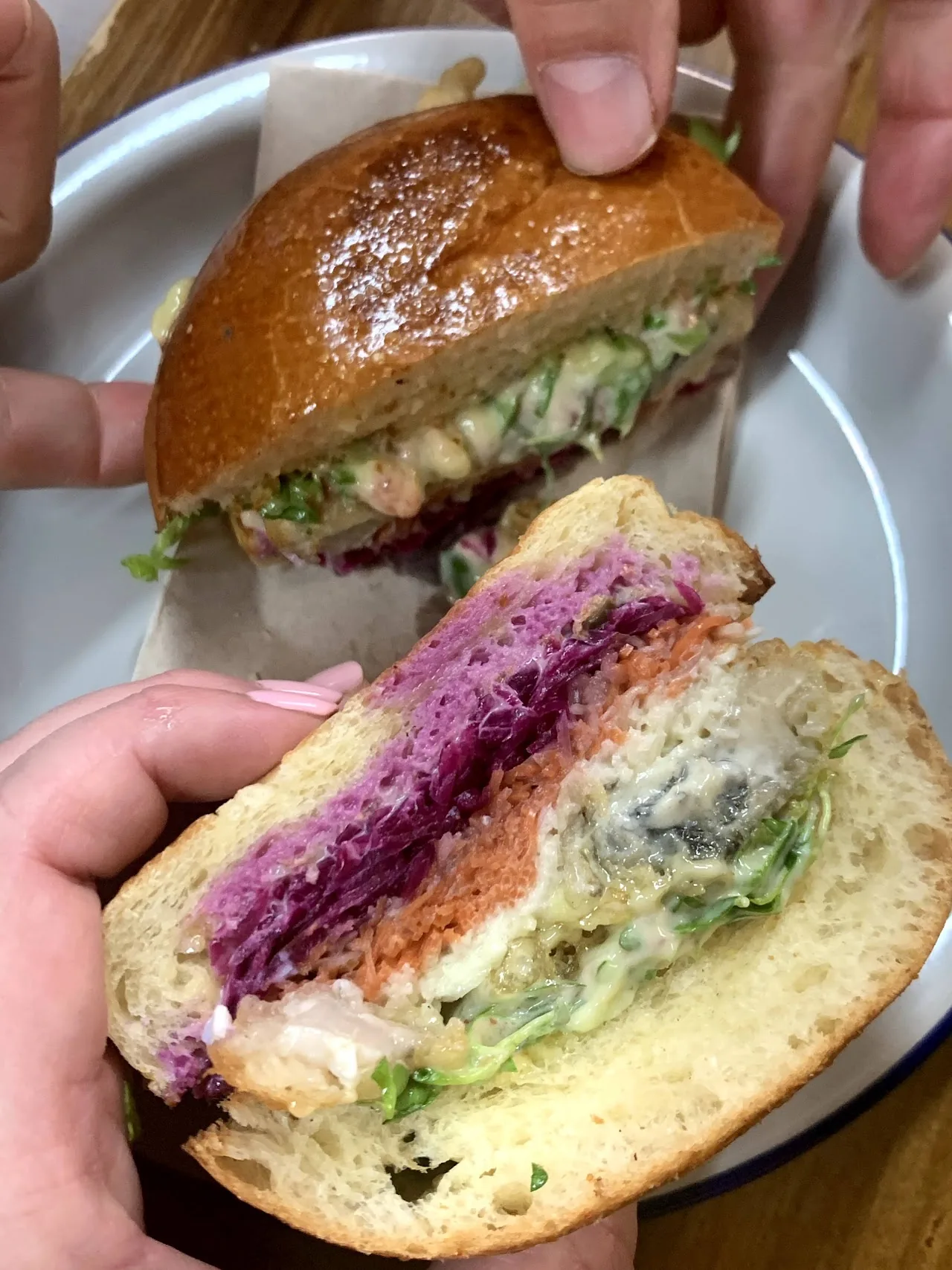 A hand holding a half sandwich with purple cabbage and greens