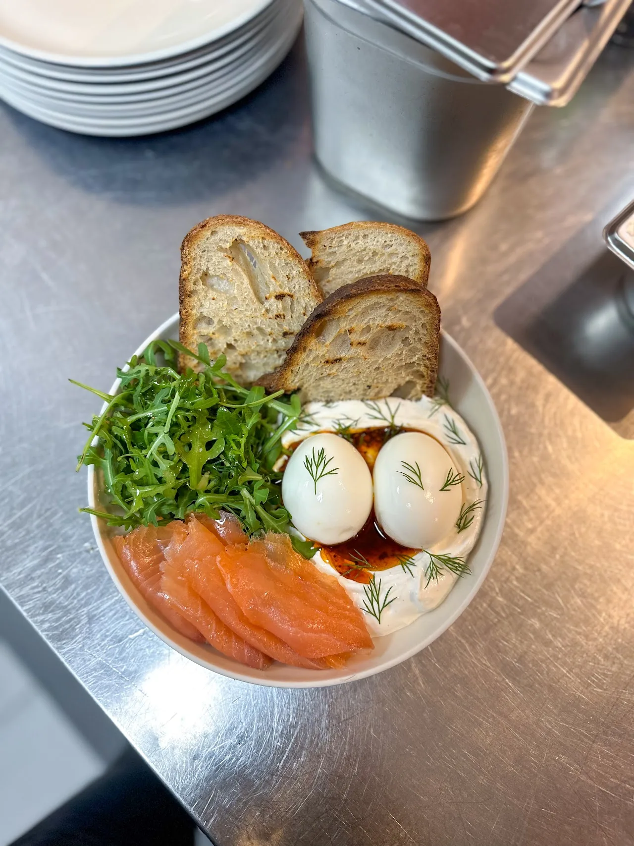 A bowl of smoked salmon with eggs and crusty bread slices