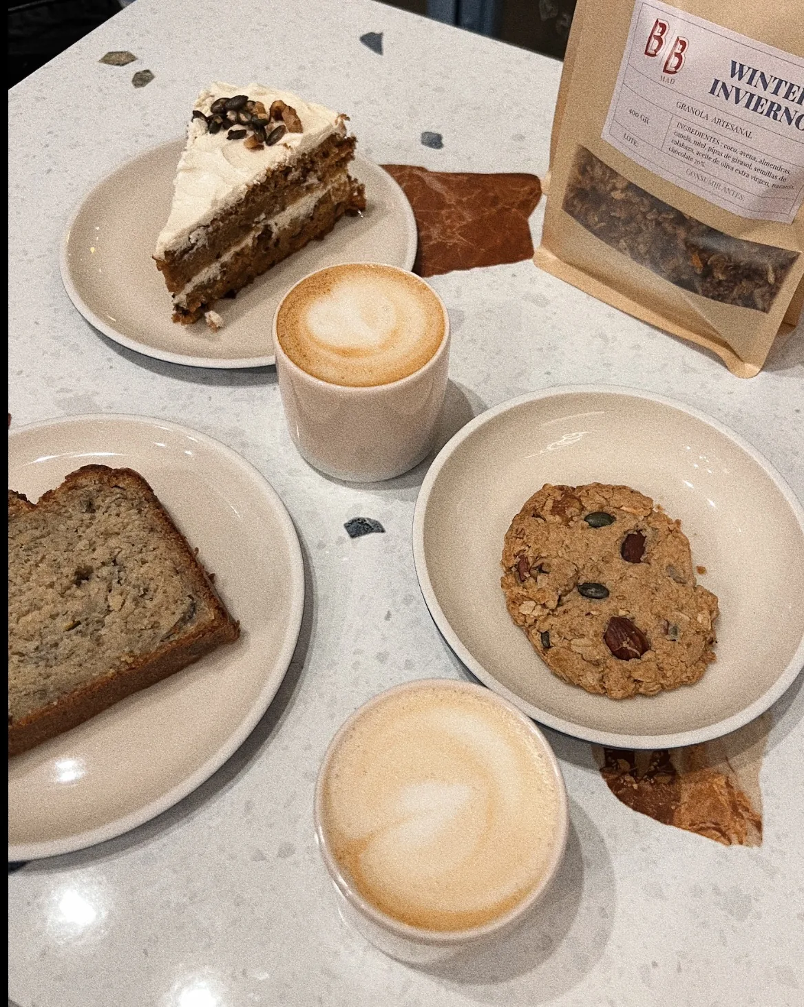 A slice of layered cake, banana bread, and a cookie on small plates