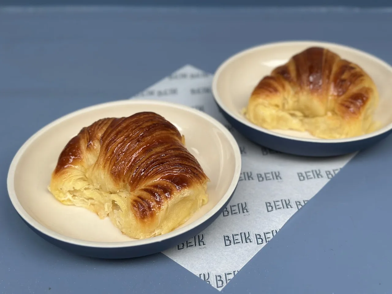Two golden croissants on small plates