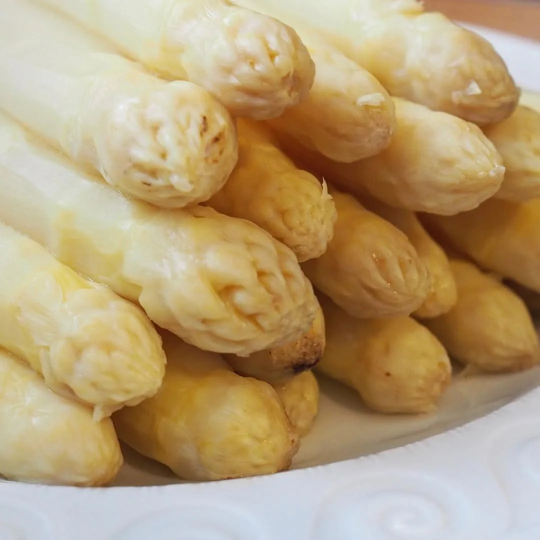 Peeled white asparagus spears on a white plate