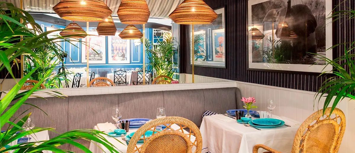 Dining room with rattan pendant lamps and tables set with blue and teal plates
