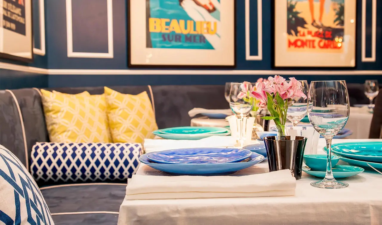 Table set with blue and turquoise plates, wine glasses, and pink flowers