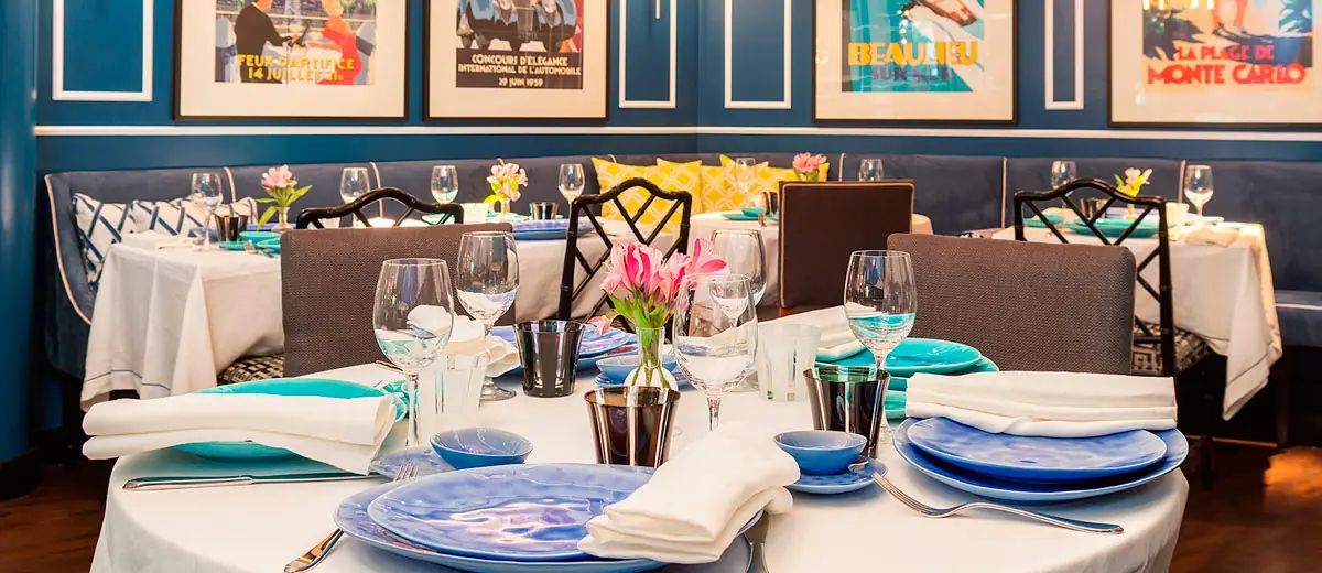 Dining room table set with blue plates under vintage travel posters