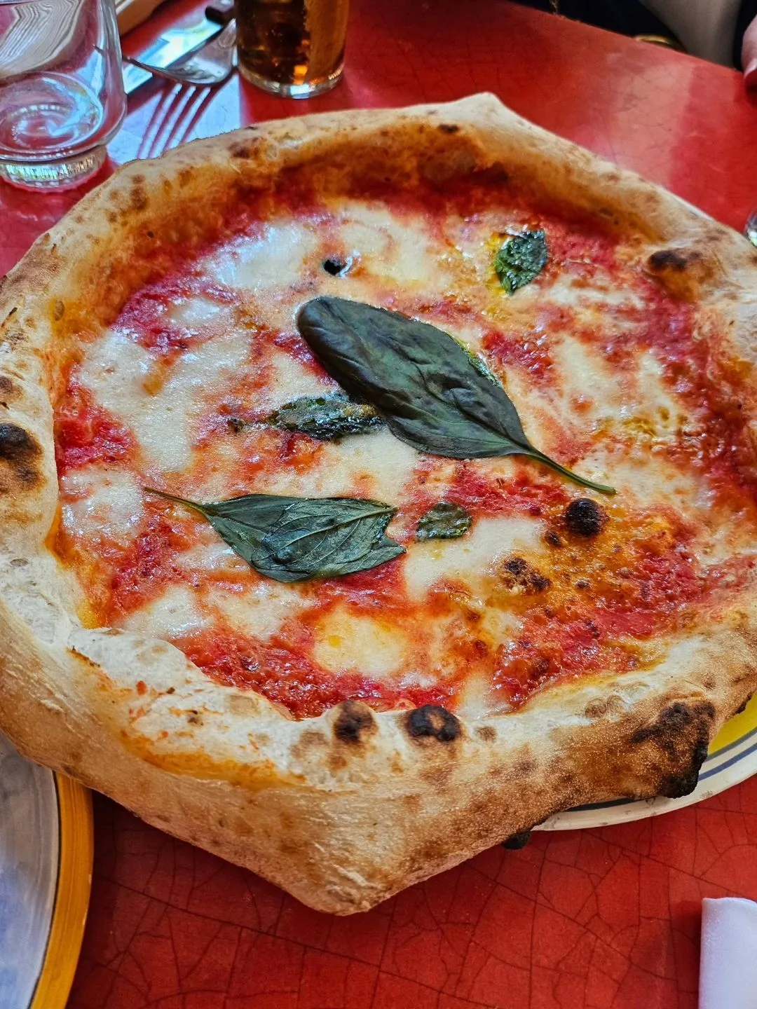 A round pizza with tomato sauce, melted cheese and two basil leaves