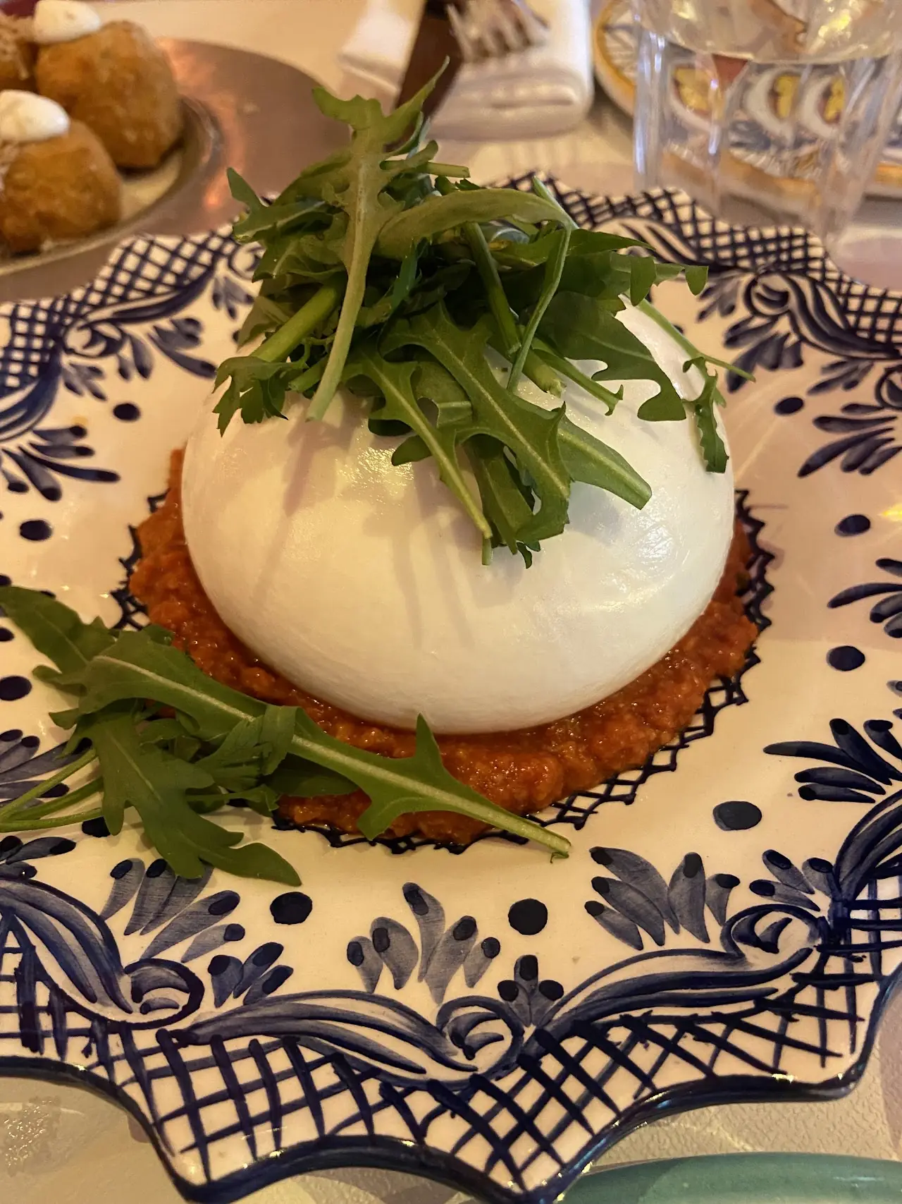 A ball of burrata topped with arugula on a slice of toast.